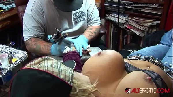 Une pornstar blonde aux gros seins sort ses énormes seins tout en se faisant tatouer le poignet vidéos sympas